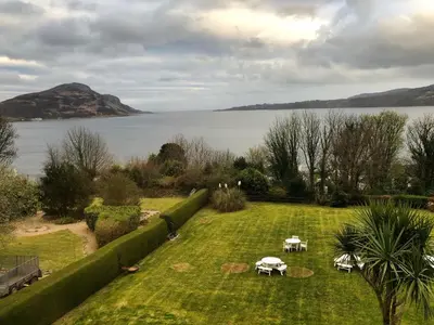 a garden with tables and a view of a lake at The Arran Lodge & Arran Sleep Huts in Lamlash