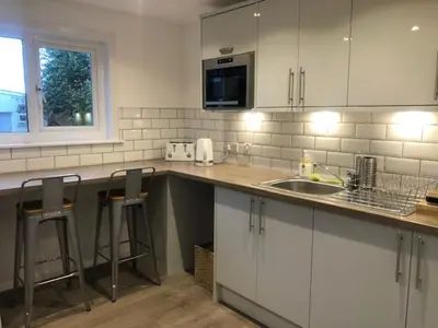 a kitchen with white cabinets and bar stools at The Arran Lodge & Arran Sleep Huts in Lamlash