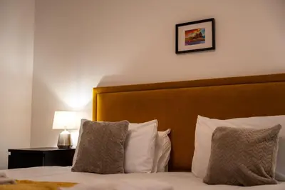 a bedroom with a bed with a wooden headboard and a lamp at Dalwhinnie Apartment in Oban