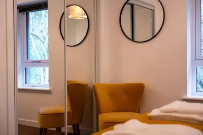 a room with two chairs and mirrors on the wall at Dalwhinnie Apartment in Oban