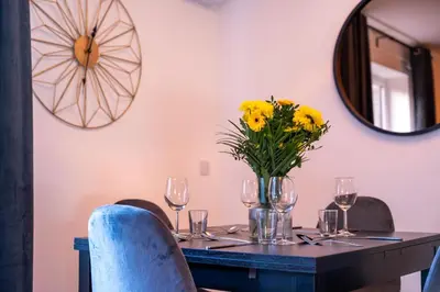 a table with a vase of yellow flowers and wine glasses at Tobermory Apartment in Oban