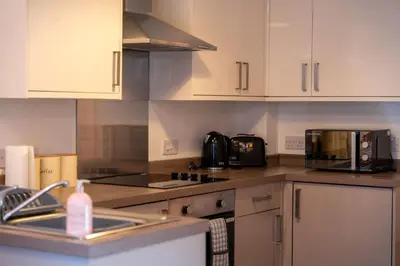 a kitchen with white cabinets and a sink and a microwave at Tobermory Apartment in Oban