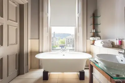 a white bathroom with a tub and a sink at Murrayfield Hotel in Edinburgh
