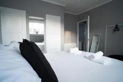 a bedroom with two beds with white sheets and towels at Darmeid House in Hartwood