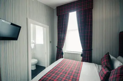 a bedroom with a bed and a window and a television at Argyll Hotel in Glasgow