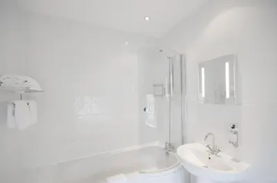 a white bathroom with a sink and a shower at Argyll Hotel in Glasgow