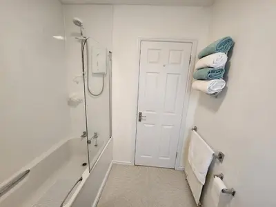 a bathroom with a shower and a bath tub with towels at 10 Ladyknowe court in Moffat