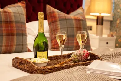 a bottle of champagne and two glasses on a bed at The Roseate Edinburgh - Small Luxury Hotels of the World in Edinburgh