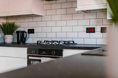 a kitchen with a black stove and white tiles at SleepLuxury ApartHOUSE in Glasgow