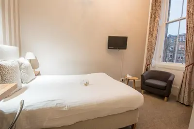 a hotel room with a bed and a chair at The Belhaven Hotel in Glasgow