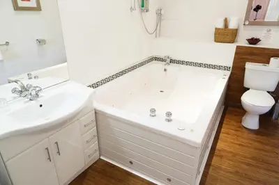 a white bathroom with a tub and a toilet at The Belhaven Hotel in Glasgow