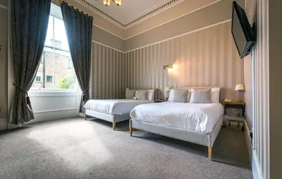 a hotel room with two beds and a window at The Belhaven Hotel in Glasgow