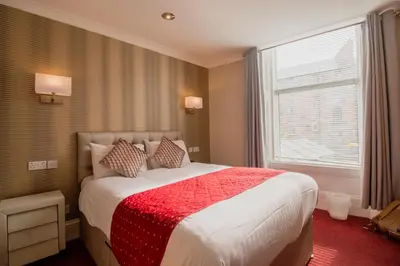 a bedroom with a large bed with a red blanket at Albion Hotel in Glasgow