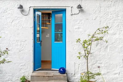 a blue door on the side of a white building at The Jaw Barn in Milngavie