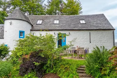 a white house with blue doors and a table at The Jaw Barn in Milngavie