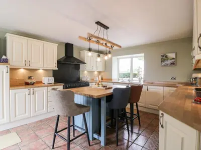 a kitchen with white cabinets and a table and chairs at Shieldhill Farm House in Falkirk