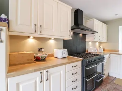 a kitchen with white cabinets and a stove top oven at Shieldhill Farm House in Falkirk