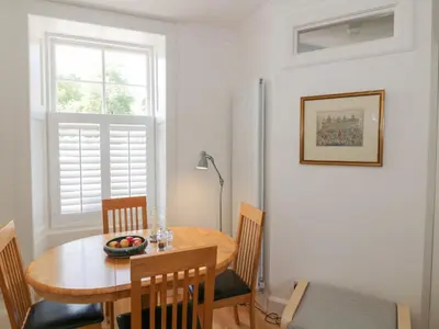 a dining room with a table and chairs and a window at 6 Kirkstyle in Biggar
