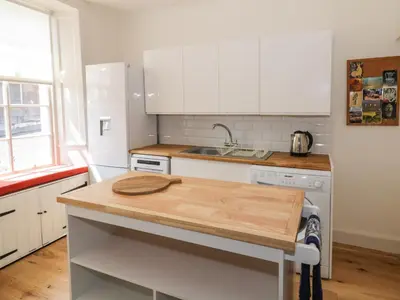 a kitchen with white cabinets and a wooden counter top at 6 Kirkstyle in Biggar