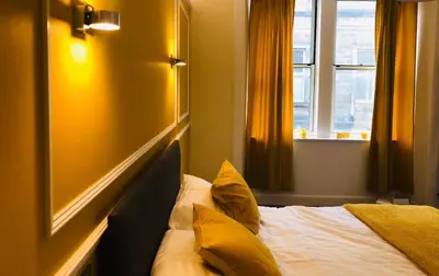 a bedroom with a bed with yellow pillows and a window at CAMPBELL 100 DUNFERMLINE in Fife