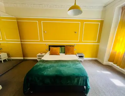 a bedroom with a bed with yellow walls at CAMPBELL 100 DUNFERMLINE in Fife