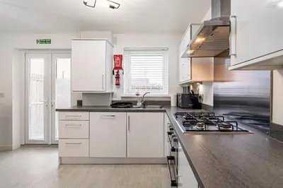 a kitchen with white cabinets and a stove at Superb 3 Bed Home Away from Home in Glasgow, just off M8 with free parking in Steps