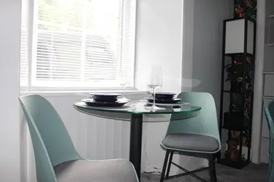 a table with two chairs and a wine glass on it at Cameronian Apartment in Stirling