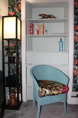 a blue chair in a room with a book shelf at Cameronian Apartment in Stirling