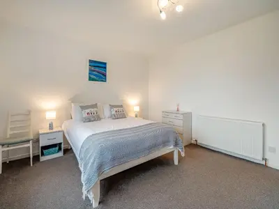 a white bedroom with a bed and two night stands at Crarae in Corrie