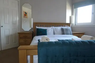 a bedroom with a large bed with a blue blanket at Aigas in Glasgow