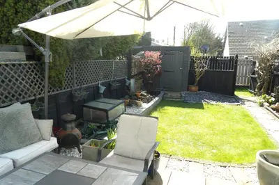 a small garden with a couch and an umbrella at Aigas in Glasgow