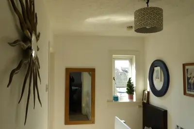 a living room with a mirror and a window at Aigas in Glasgow