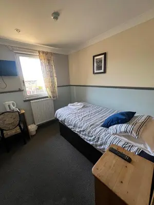 a bedroom with a bed and a table and a window at Boreland Lodge Hotel in Inverkeithing
