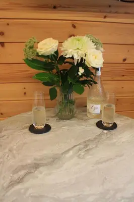 a table with two glasses and a vase of flowers at Loch View Luxury Pod in Connel