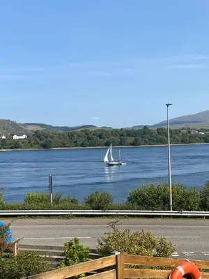 a sailboat on a river with a boat in the water at Loch View Luxury Pod in Connel