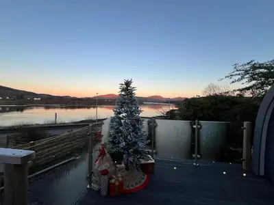 a christmas tree on a deck next to a lake at Loch View Luxury Pod in Connel