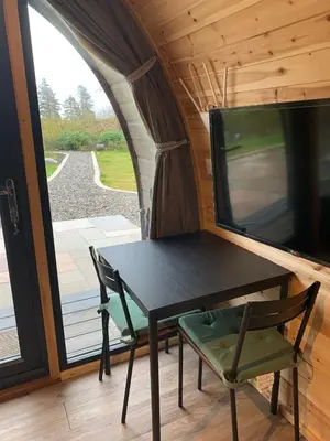 a table and chairs in a tiny house with a window at Red Squirrel Pod with Hot Tub in Oban