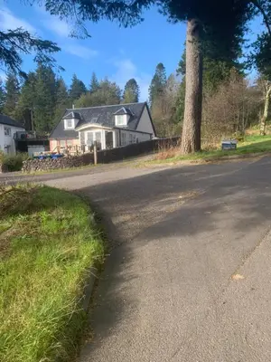 an empty road with a house and a tree at Red Squirrel Pod with Hot Tub in Oban