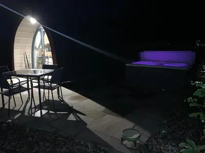 a dark room with a table and a bed at Red Squirrel Pod with Hot Tub in Oban