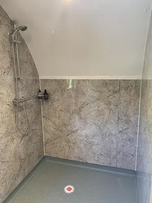a shower in a bathroom with a stone wall at Tawny Owl Pod with Hot Tub in Oban