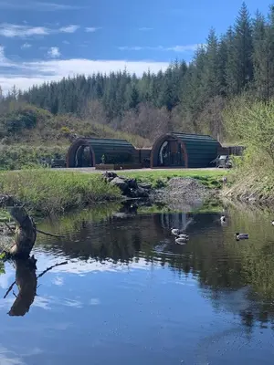 a river with ducks in the water with a train at Tawny Owl Pod with Hot Tub in Oban