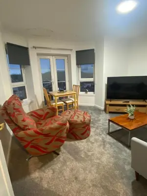 a living room with a chair and a television at Prime Duloch Bridge View by TBA in Dunfermline