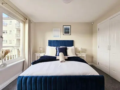 a bedroom with a large bed with a blue headboard at Modern 5 Bedroom Townhouse with Free Parking in Glasgow