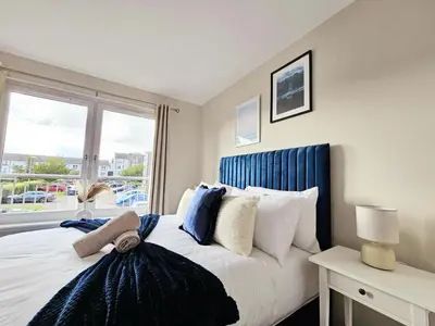 a bedroom with a bed with a blue headboard and a window at Modern 5 Bedroom Townhouse with Free Parking in Glasgow