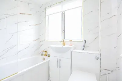 a white bathroom with a sink and a tub and a window at Doralan in Bishopbriggs