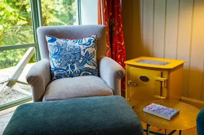 a chair with a pillow sitting next to a window at Stable Cottage, Gartocharn, Loch Lomond in Alexandria