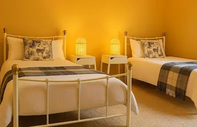 two beds in a room with yellow walls at Scottish Highland Cottage Tyndrum Upper Station in Crianlarich