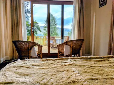 a bedroom with a bed and two chairs and a large window at Scottish Highland Cottage Tyndrum Upper Station in Crianlarich