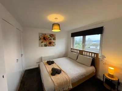 a bedroom with a bed with a large window at The Wee Hoose Rhu in Rhu