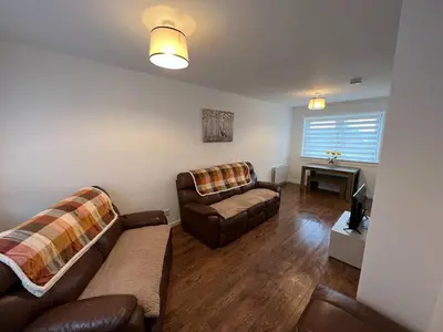 a living room with two couches and a television at The Wee Hoose Rhu in Rhu